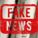 Red stamp with the words 'FAKE NEWS' over blurred newspaper background