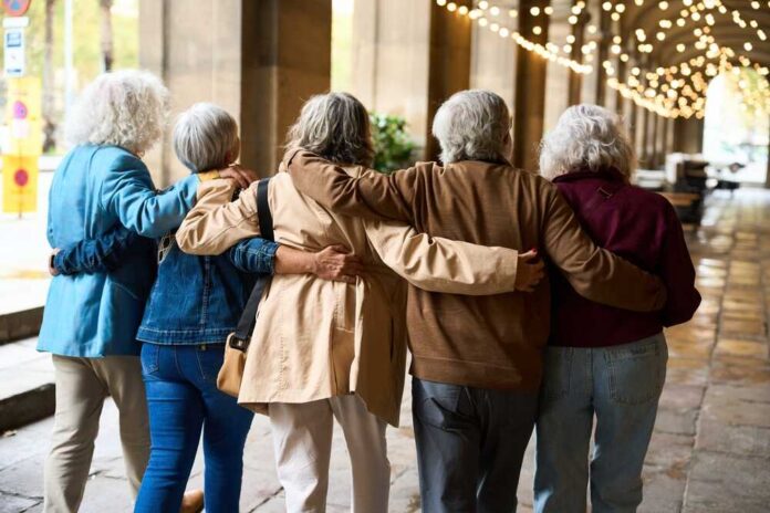 Seniors,Walking,Arm,In,Arm,Through,A,City,Colonnade,,Older Group of elderly friends walking arm in arm outdoors