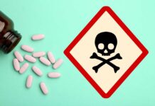 A bottle of pills spilled next to a poison warning sign