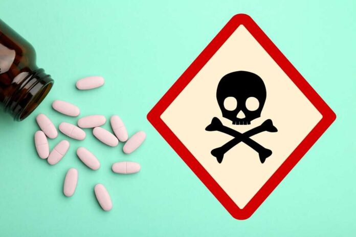 A bottle of pills spilled next to a poison warning sign