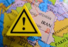 American Forces Strike Back: Iran’s Fury Unleashed A yellow warning sign placed on a map highlighting Iran