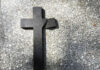 Broken black cross on a gray surface.