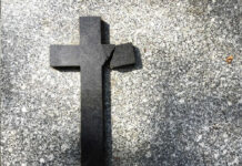 Pastor’s Bible Brand Collides With Phone Receipts Broken black cross on a gray surface.