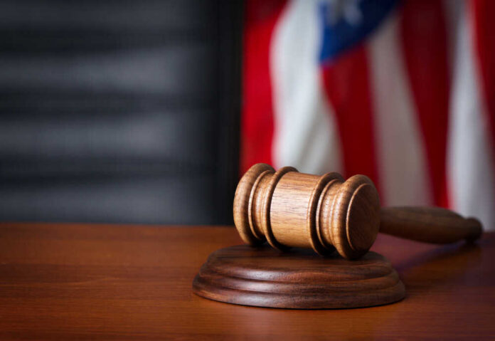 Gavel,On,Court,Desk A wooden gavel resting on a sound block with an American flag in the background