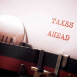 War Tax Hits American Homes Hard A typewriter with a paper displaying the words 'TAXES AHEAD'