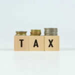 Judge Says THIS White House ‘Fee’ Is a Tax Blocks spelling 'TAX' with coins stacked beside them