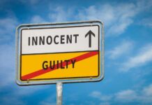 A road sign displaying 'INNOCENT' with an arrow pointing up and 'GUILTY' crossed out