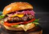 Burger Chain’s Grass-Fed Gamble Close-up of a gourmet cheeseburger with lettuce, tomato, and pickled onions