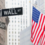 Street signs for Wall Street and Broad Street with American flags