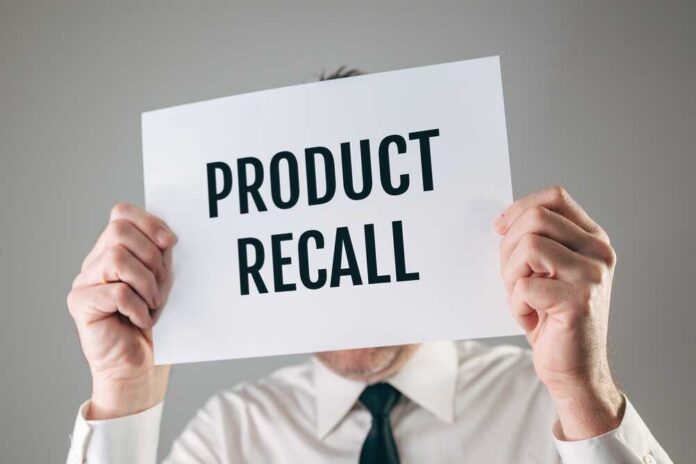 Person holding a sign reading product recall