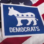 Blue State Governor’s Decision Spurs Election Firestorm Democrats emblem on an American flag background.