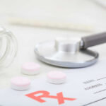 Mystery Gunk Triggers Massive Pill Recall A stethoscope, prescription pad, and pink tablets on a table