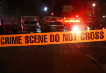 Ambush Chaos: 11-Year-Old Caught In Gunfire Crime scene tape with emergency vehicles in background.