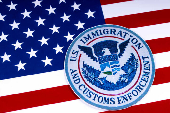 shutterstock_1055129177 US Immigration and Customs Enforcement badge on flag