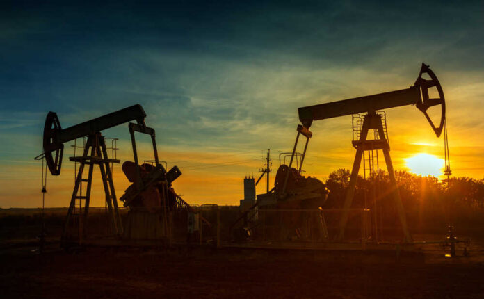 Two,Working,Oil,Pumps,Silhouette,Against,Sunset Graphical representation of oil prices with oil pumps at sunset