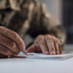 NOW: Car Payment Crisis Explodes A hand writing on a notepad with a pen