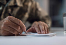 A hand writing on a notepad with a pen
