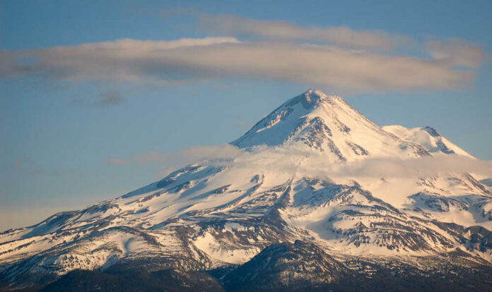 Snow-covered mountain peak partially obscured by clouds