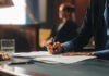 AI Axe Falls at Huge Employer Person writing at desk with documents and glass.