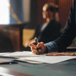 AI Axe Falls at Huge Employer Person writing at desk with documents and glass.