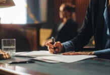 AI Axe Falls at Huge Employer Person writing at desk with documents and glass.