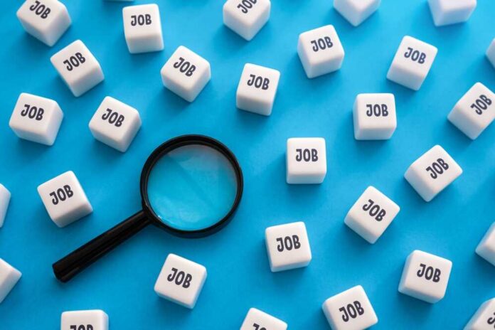 Magnifying glass among cubes labeled job on blue background