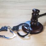 Gavel and handcuffs on wooden table