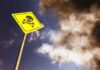 Rooftop Bacteria Kills Five — Who’s Liable? Yellow skull and crossbones warning sign against smoky sky