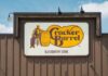 Sign for Cracker Barrel Old Country Store featuring a man sitting on a barrel