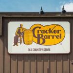 Sign for Cracker Barrel Old Country Store featuring a man sitting on a barrel