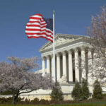 Ballots Blocked? Supreme Court Holds The Key U.S. Supreme Court building with an American flag and cherry blossom trees