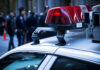 Wrong Man? ICE Shooting Sparks Fury Police car roof with lights, officers in background.