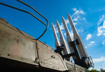 Missiles silhouetted against American flag background with sunset.