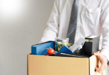 Federal Exodus Warning Lights Flash Person holding a box of personal office items.