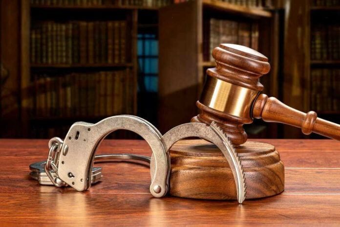 shutterstock_2052225677 Wooden gavel and handcuffs on a table.