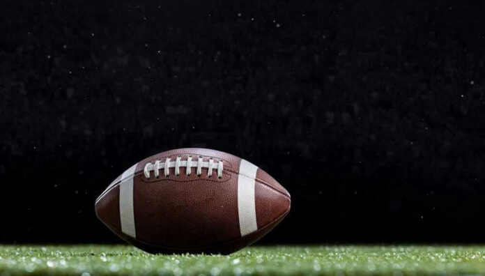shutterstock_21715530951 Close-up of a football on a grassy field.
