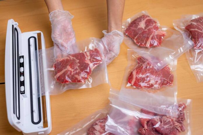 Raw,Beef,Meat,Sealed,In,Plastic,Shrink,Wrap,With,Vacuum Hands wearing gloves vacuum sealing meat in plastic bags