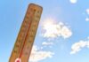 America Boils: Hottest Month Ever Thermometer displaying high temperature against a bright sun