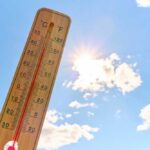 Thermometer displaying high temperature against a bright sun
