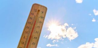 Thermometer displaying high temperature against a bright sun