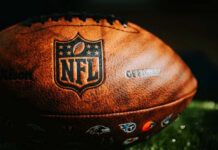 Terrifying NFL Crisis Revealed: One In Four? Close-up of an NFL football on grass.
