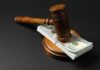 Judge’s gavel resting on a stack of US hundred-dollar bills