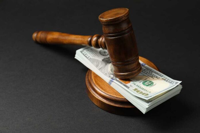 Law,Gavel,With,Stack,Of,Dollars,On,Black,Table,,Closeup Judge’s gavel resting on a stack of US hundred-dollar bills