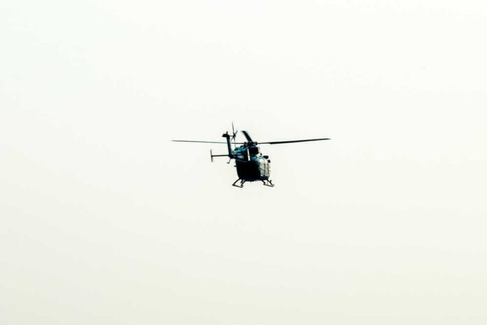 Military Apache helicopter flying against a blue sky