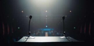 View of a podium with microphones in a dimly lit auditorium