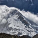 Snow-covered mountain peak partially obscured by clouds