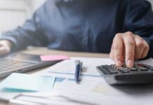 Housing Squeeze Forces Record Boomerang Kids Person using a calculator while working on a laptop and reviewing documents