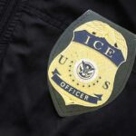 ICE Shooting Clash: Constitution In Crosshairs Close-up of an ICE officer badge on a black jacket
