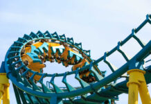 Beloved Park Shutters — What Vanishes Next? Roller coaster train twists through a teal and yellow loop