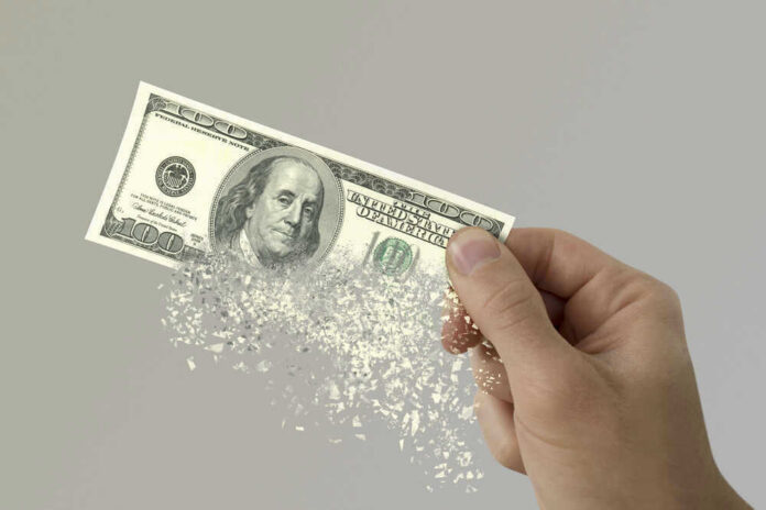 shutterstock_580278601 Hand holding a disintegrating hundred dollar bill.